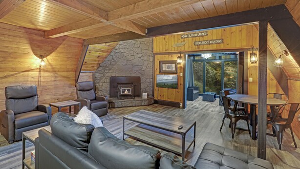 Un intérieur chaleureux de chalet en bois, avec des canapés en cuir, une cheminée en pierre et un coin repas.