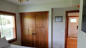Ein Schlafzimmer mit einem großen Bett, einem Holzschrank und einem kleinen Fenster.