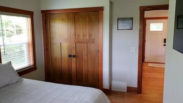 Une chambre avec un grand lit, une armoire en bois et une petite fenêtre.
