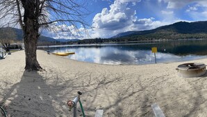 Vista de un lago con playa arenosa, una fogata y un bote.