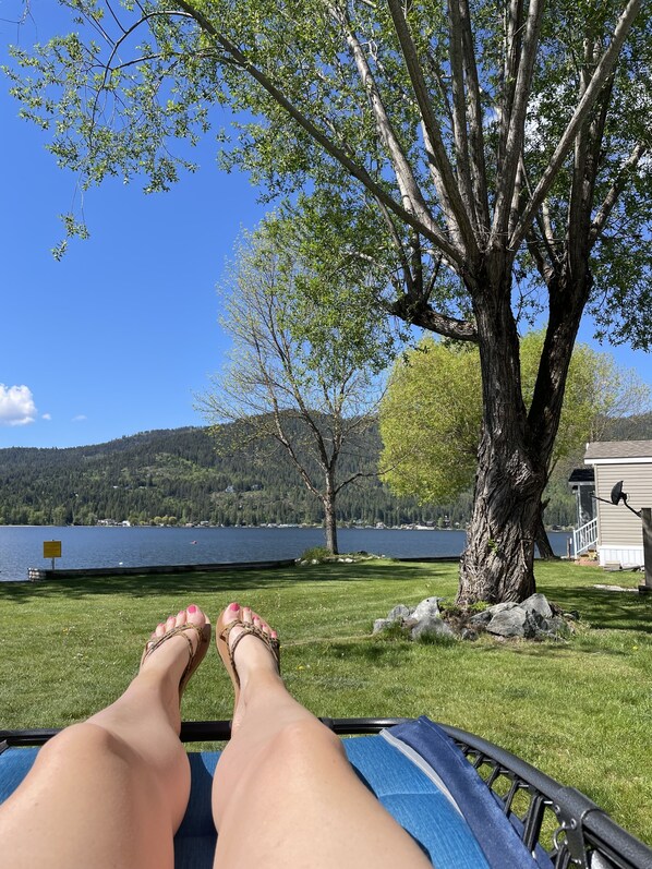 A person relaxing on a lounge chair with a view of a lake and mountains.