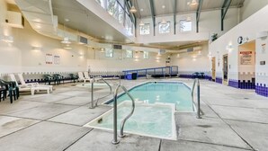 Une piscine intérieure dotée de plusieurs couloirs de nage, de chaises longues et d’un haut plafond laissant entrer la lumière naturelle.