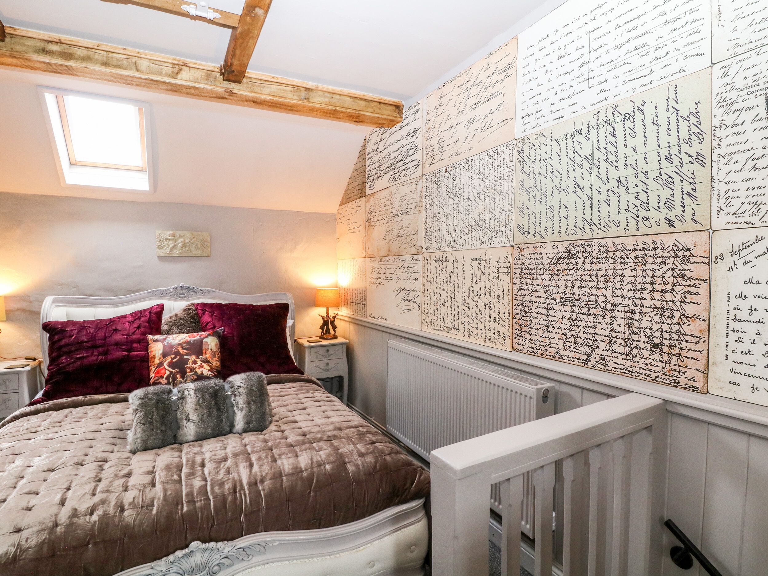 A bedroom with a large bed, a wooden ceiling, a skylight, and a wall covered with handwritten notes.