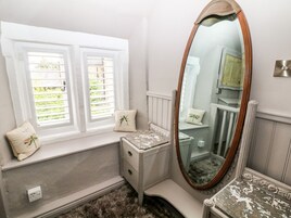 Un baño con tocador, un espejo grande y dos ventanas con contraventanas.