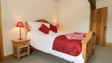 A neatly made bed with a wooden headboard, two bedside tables with lamps, and a wooden wardrobe.