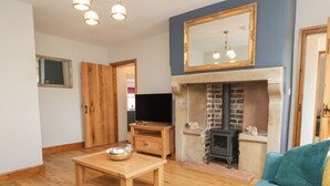 A living room with a fireplace, wooden furniture, and a television.