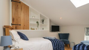 A bedroom with a bed, bedside table, lamp, TV, and a wooden wardrobe.