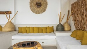 A modern living room with a white sofa, yellow cushions, a wooden coffee table, and decorative woven baskets. - Verandah Studios (Playa del Carmen)
