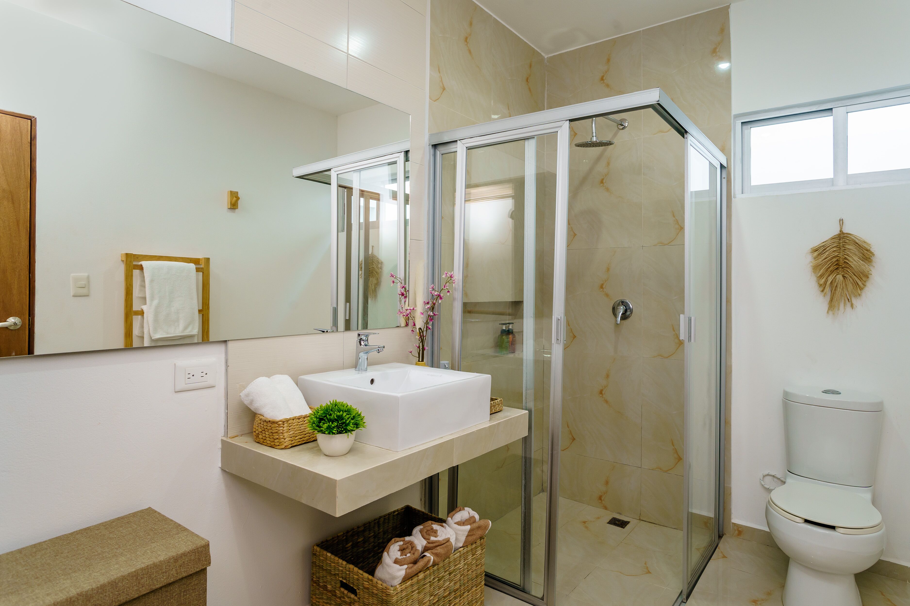A modern bathroom with a glass-enclosed shower, a white sink, and a toilet.