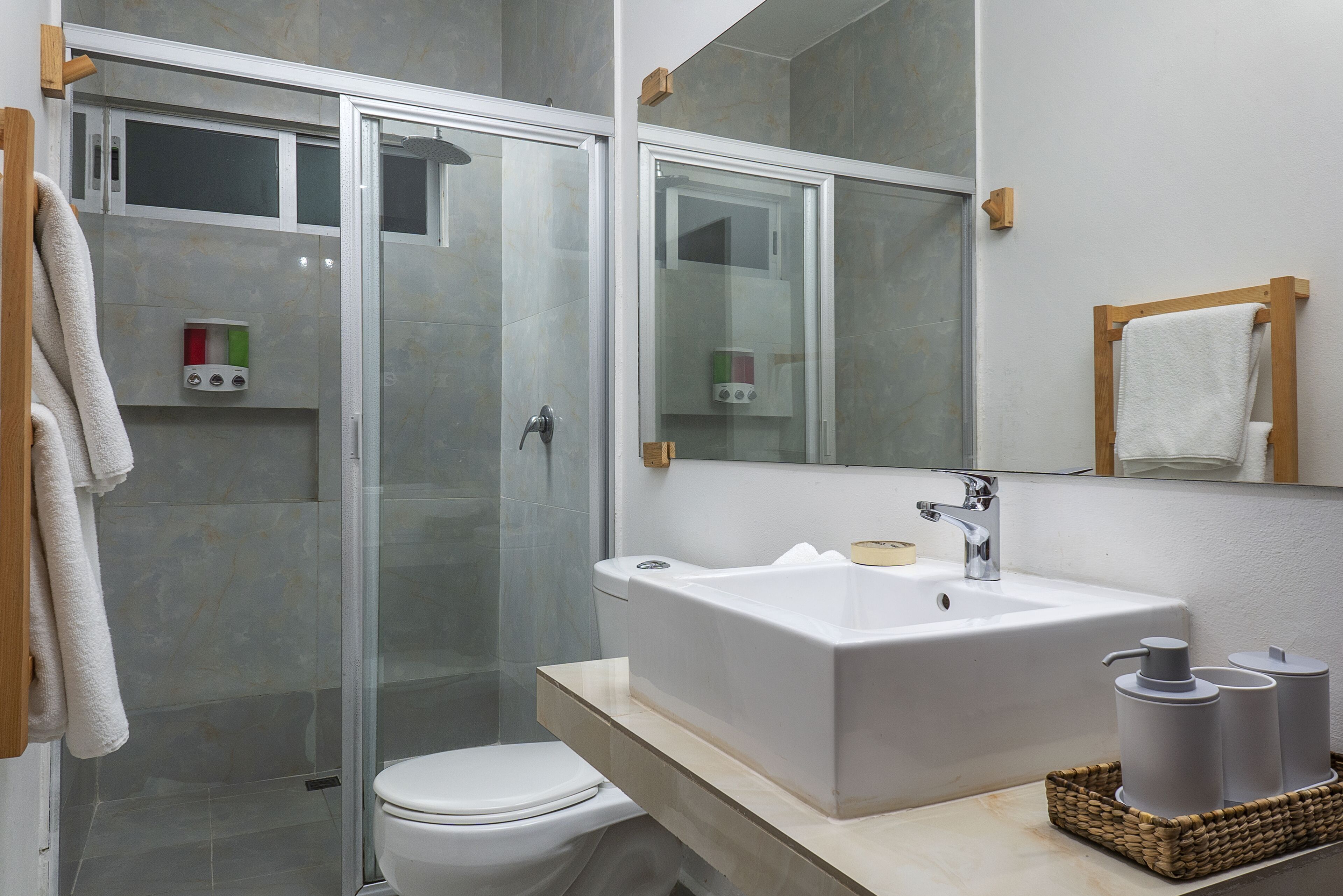A modern bathroom with a glass shower enclosure, a white sink, and a toilet.
