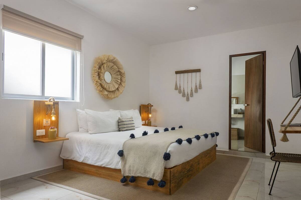 A bedroom with a bed, bedside table, wall decor, and a television.