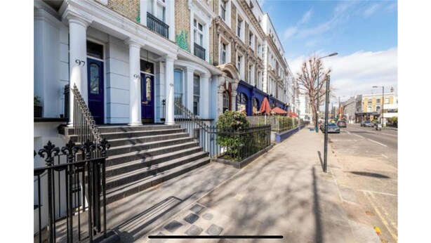 A row of traditional British townhouses with uniform facades, a clear sidewalk, and a street view. - Flat close to Portobello Market (London)