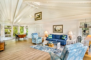 Un salon spacieux doté d’un plancher en bois, d’un canapé bleu, d’une table basse et d’un coin repas avec des chaises et une table.