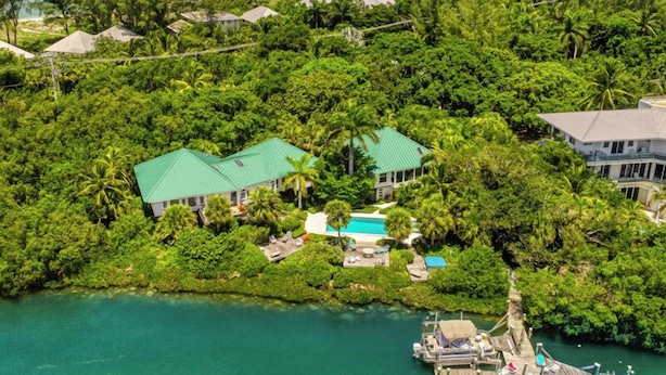 Vista aérea de un resort tropical con varias edificaciones, una piscina y un muelle con barcos.