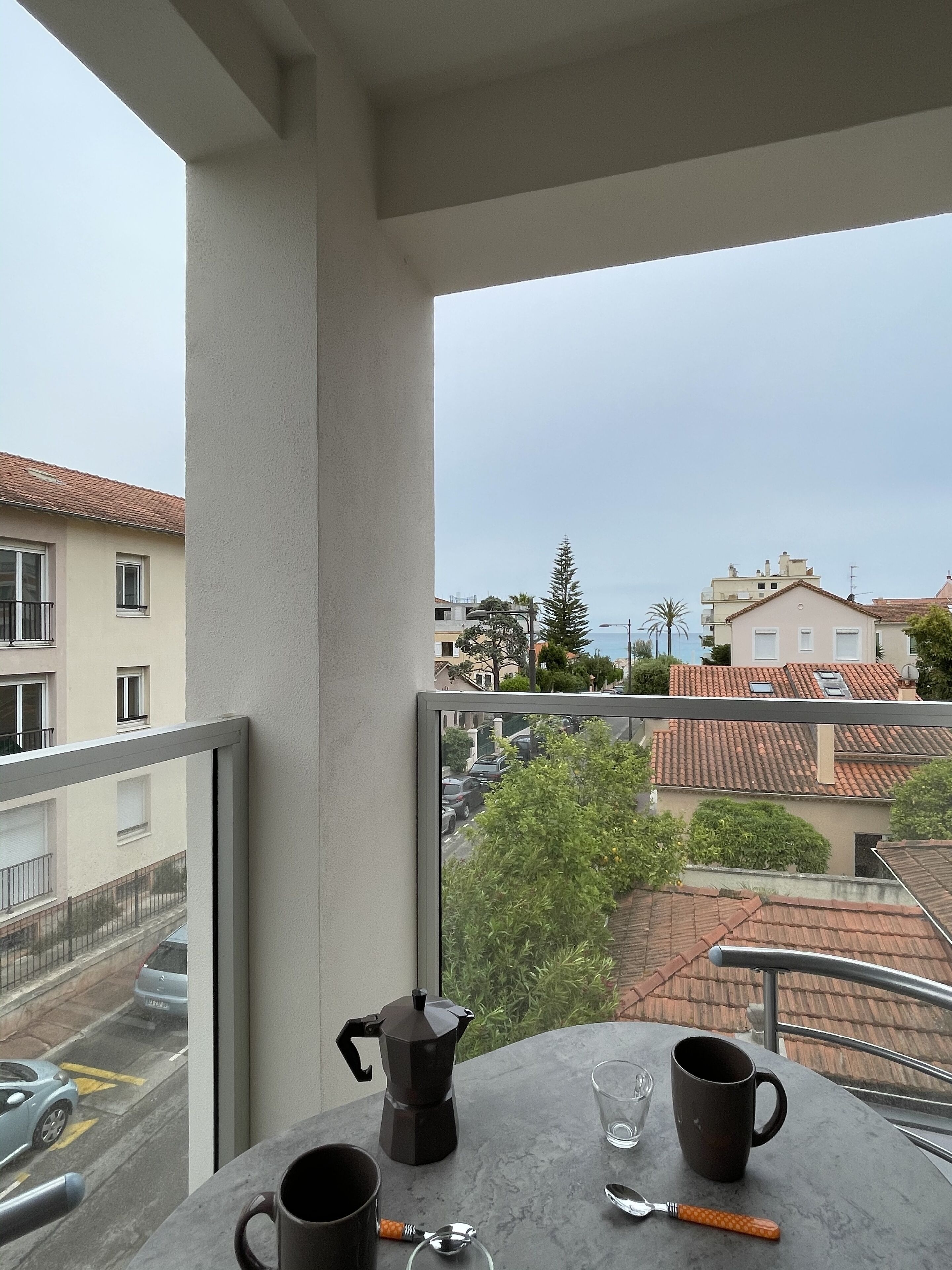 A balcony with a table, two coffee cups, and a coffee pot.
