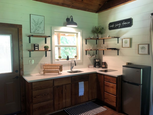 A kitchen with wooden cabinets, a sink, a refrigerator, and various kitchen items.