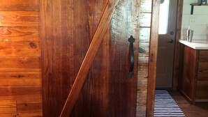 A wooden door with a diagonal handle, a red and white striped blanket on a bed, and a wooden floor.