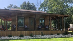 A wooden cabin with a porch, two ATMs, and a stone wall in the background.