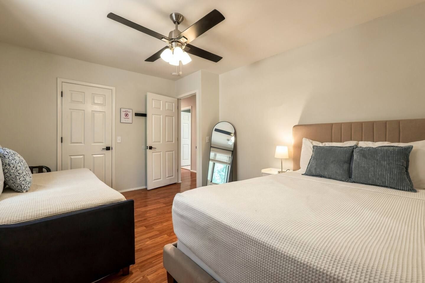 Guest bedroom with comfortable bed setup and wood-style flooring.