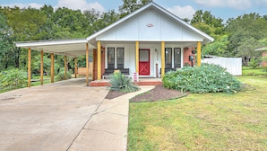 A single-story house with a covered porch, a red door, and a brick exterior.