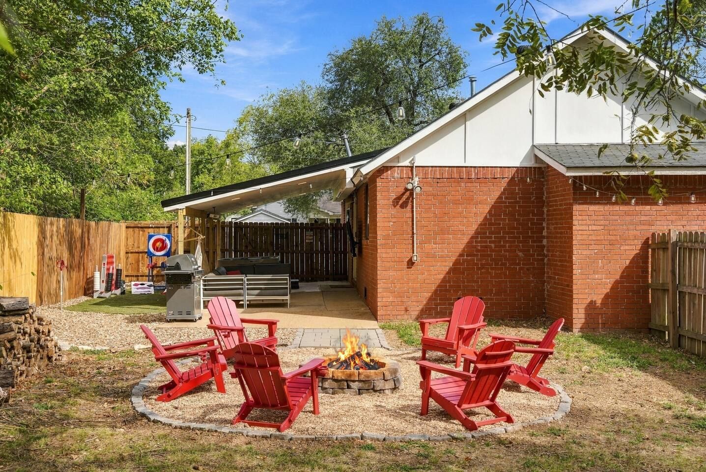 Ein Garten mit Grillplatz, Sitzgelegenheiten im Freien und einer überdachten Terrasse.