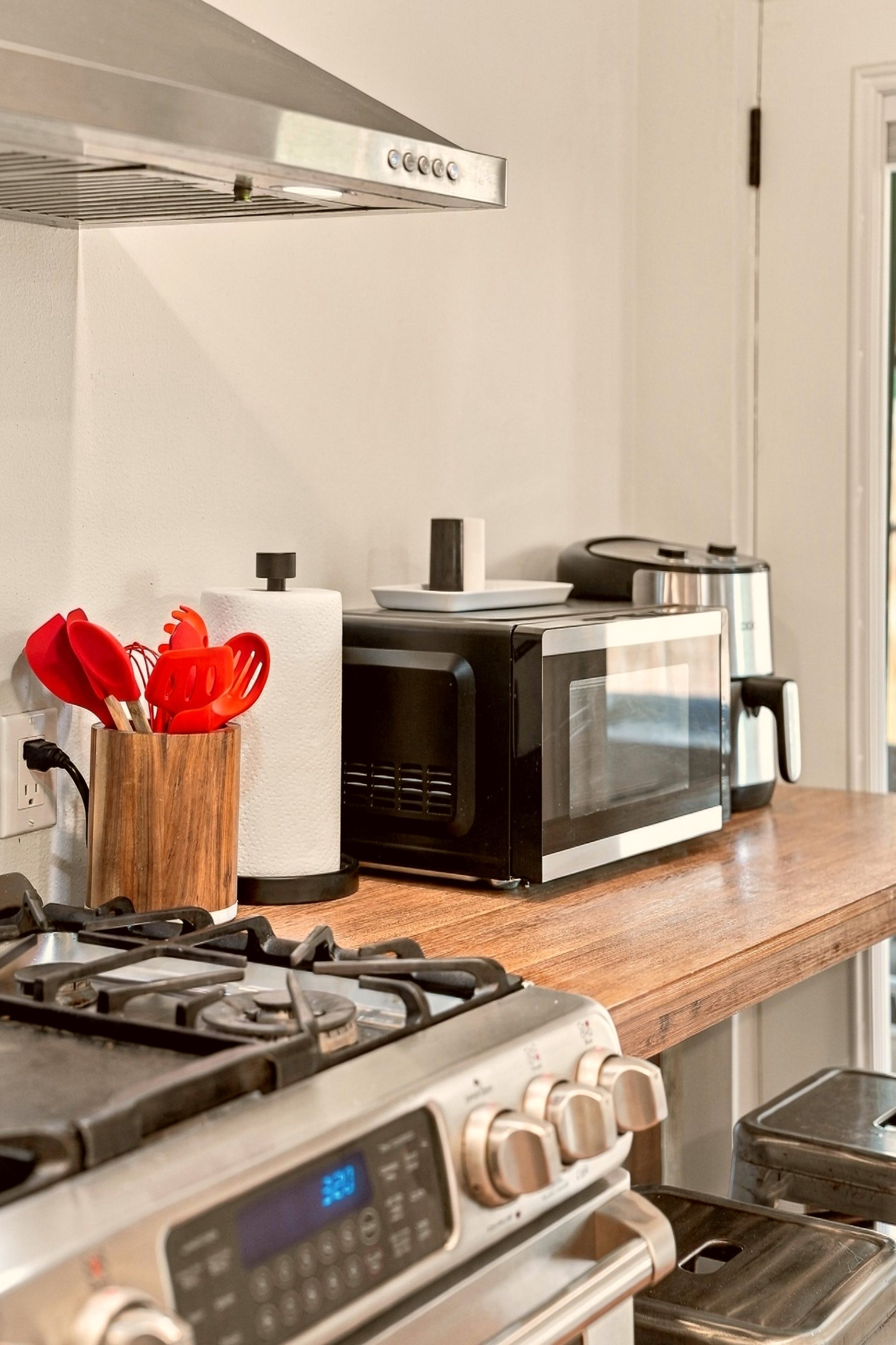 Una cocina con estufa, microondas y tostadora sobre una encimera de madera.