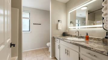 Full bathroom featuring a long vanity with LED illuminated mirror, spacious counter, and tile flooring.