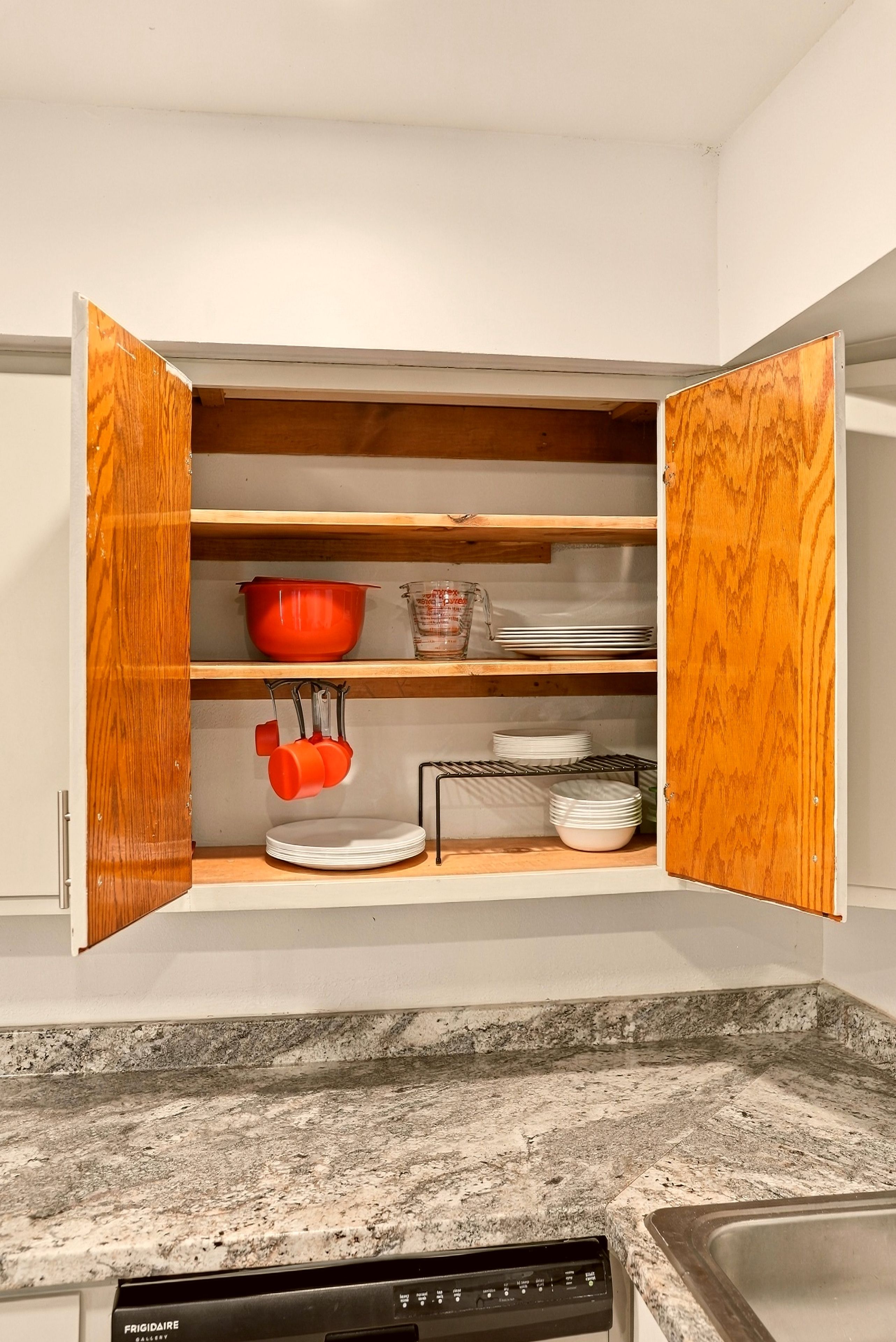 Una cocina con un armario empotrado de madera, encimera de granito y lavavajillas.