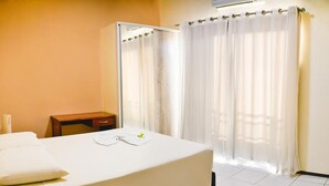 Une chambre d’hôtel comprenant un lit, une table de chevet, une chaise et un espace douche.