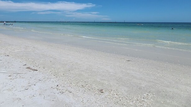 En strand med klart, blåt vand og en sandet kystlinje.