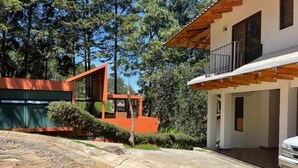 A modern house with a stone driveway, a wooden balcony, and a garage.