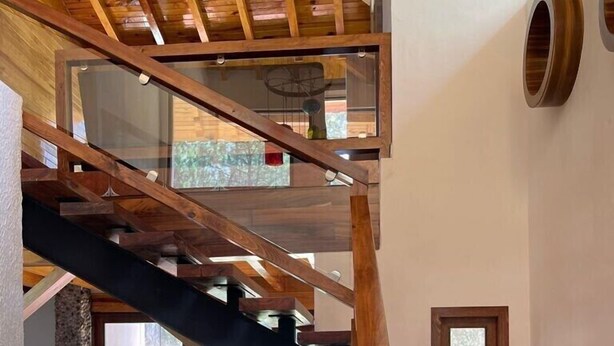 A wooden staircase with a glass enclosure leading to a second floor.