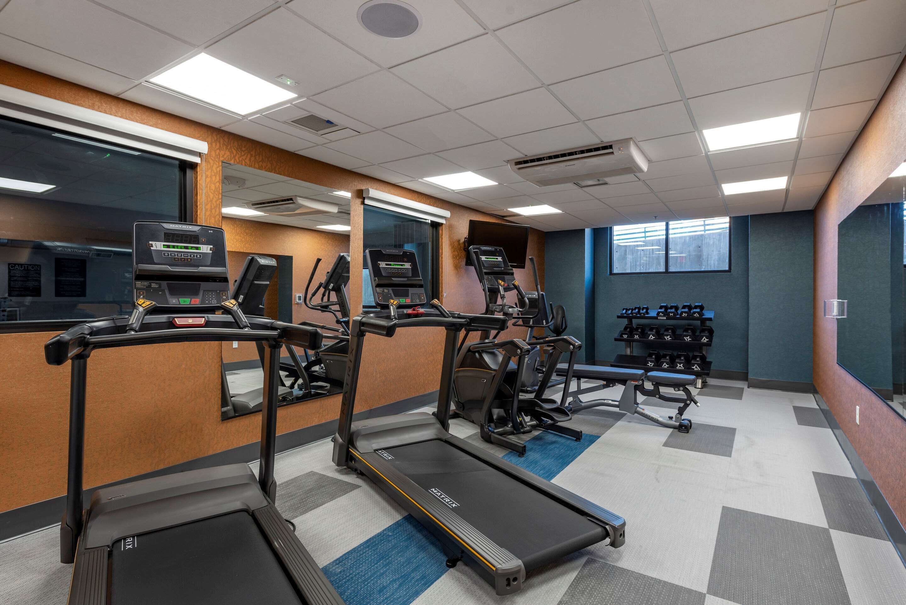 Un gimnasio con cintas de correr, elípticas y una zona de pesas.