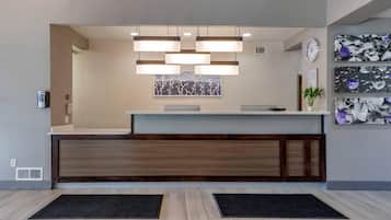 A reception desk with a modern design, a clock, and artwork on the wall.