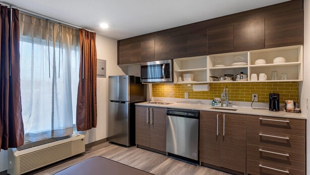 Une cuisine moderne équipée d’appareils électroménagers en acier inoxydable, de meubles en bois et d’un four à micro-ondes encastré.
