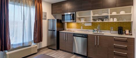A modern kitchen with stainless steel appliances, wooden cabinets, and a built-in microwave.