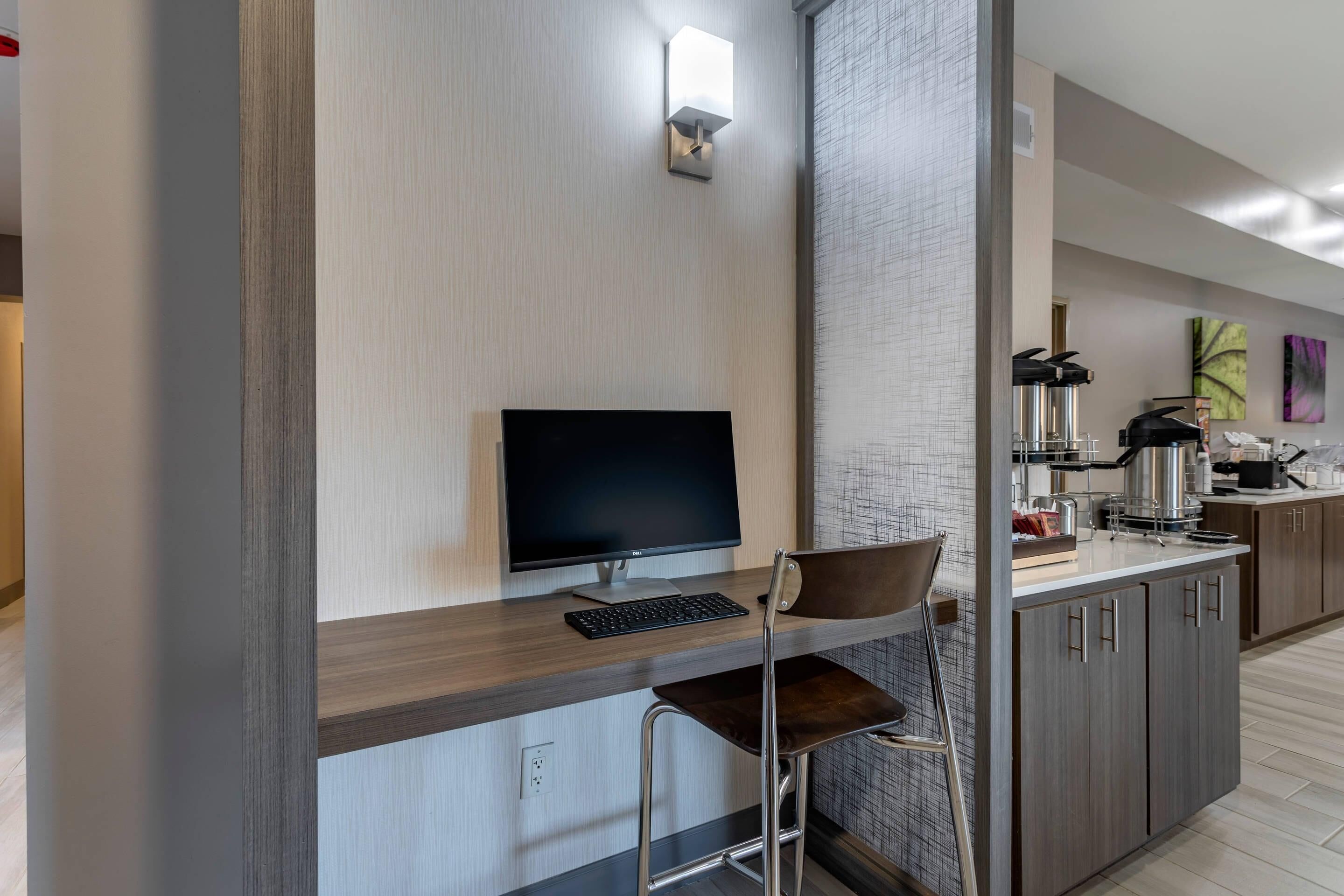 A modern kitchen with a built-in flat-screen TV, a wooden countertop, and a bar stool.