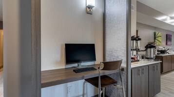 A modern kitchen with a built-in flat-screen TV, a wooden countertop, and a bar stool.