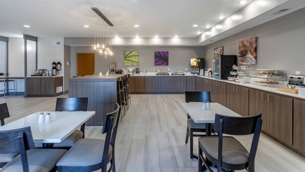 A modern kitchen with a central island, bar stools, and a dining area with tables and chairs. - MainStay Suites Lebanon - Nashville Area (Lebanon)