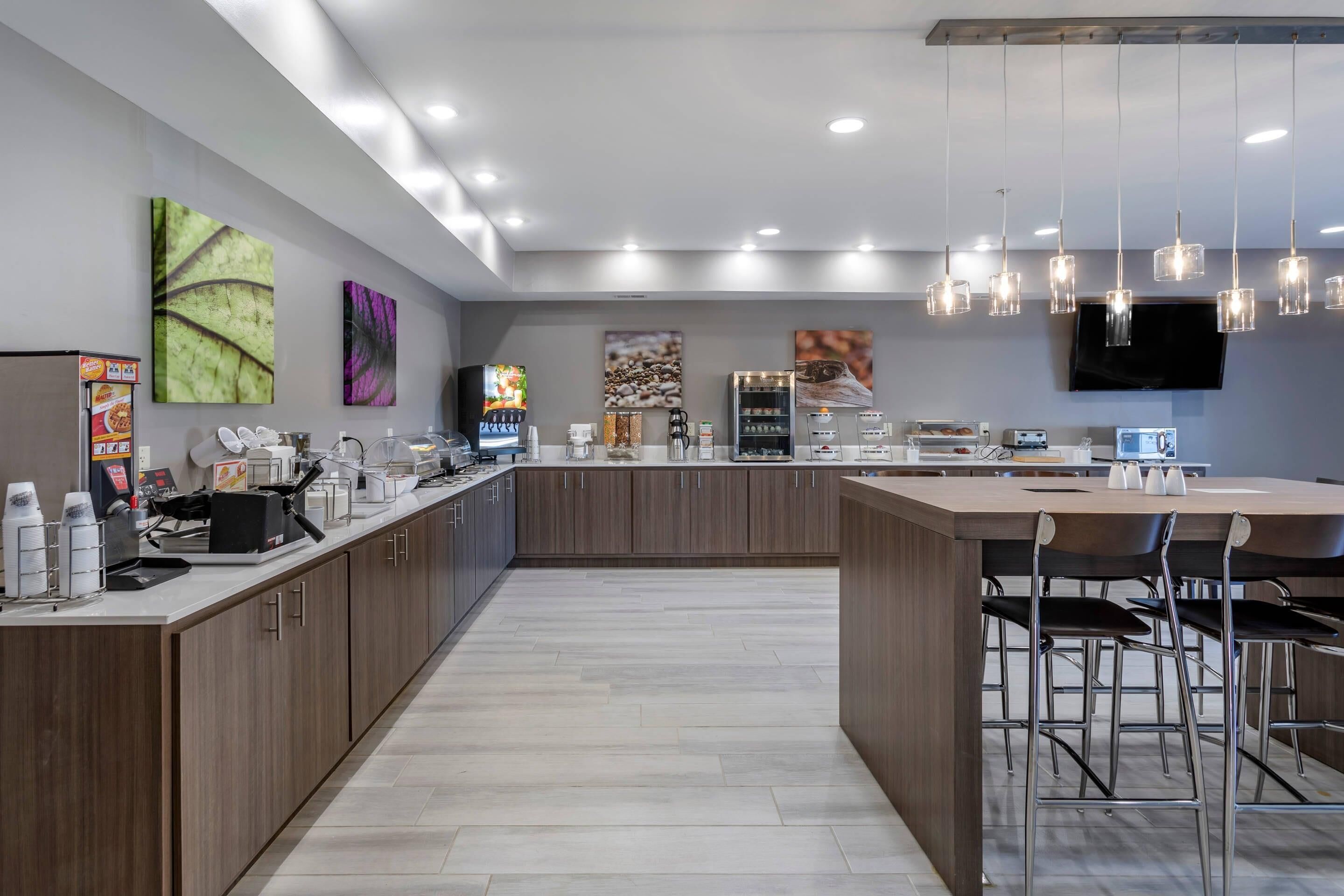 Una cocina moderna con una isla central, taburetes de bar y un televisor de pantalla plana en la pared.