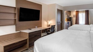 A hotel room with a bed, a desk with a chair, a TV mounted on the wall, and a kitchenette area. - MainStay Suites Lebanon - Nashville Area (Lebanon)