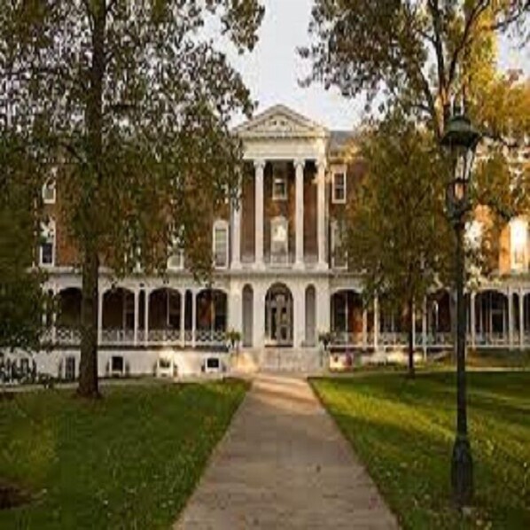A large building with a central entrance, surrounded by trees and a pathway leading to it. - avid hotel Salem by IHG (Salem)