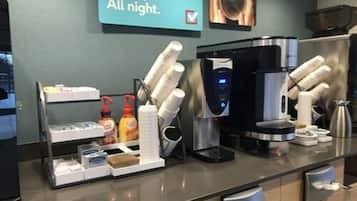 Un espace d’accueil d’hôtel équipé d’une machine à café, d’une bouilloire et d’un distributeur de café. On y trouve également des condiments et des serviettes en papier sur le comptoir.