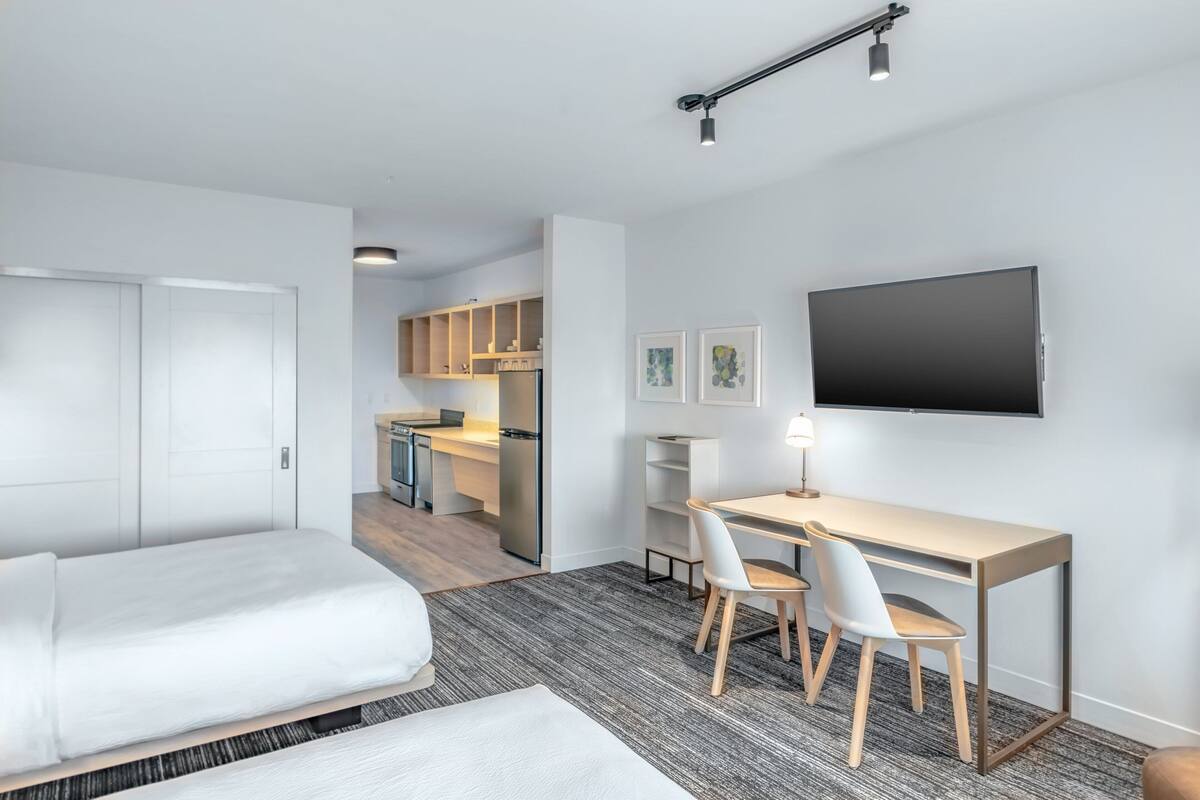 A modern hotel room with a bed, a desk, and a TV.