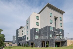 A modern multi-story building with a mix of stone and light-colored facades, multiple balconies, and a flat roof. - TownePlace Suites by Marriott Dallas Rockwall (Rockwall)