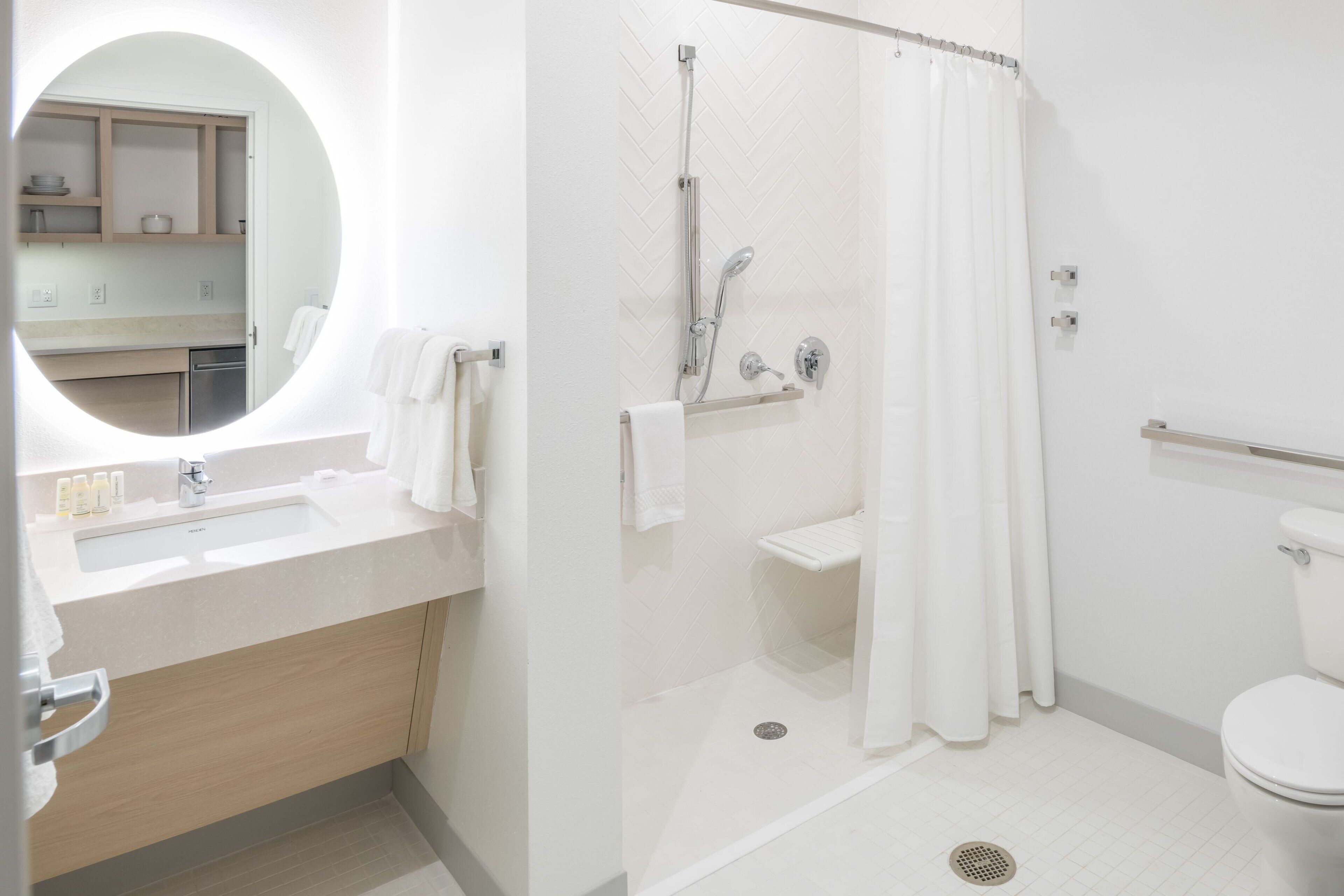 A modern bathroom with a sink, mirror, shower, and toilet.