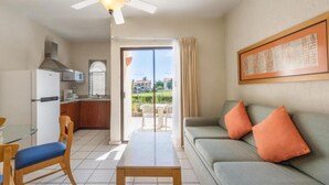 Ett kompakt bostadsutrymme med ett litet kök, en matplats och en soffa med orange kuddar.
