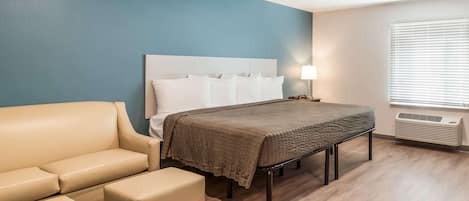 Een hotelkamer met een bed, een slaapbank, een nachtkastje en een raam met jaloezieën.