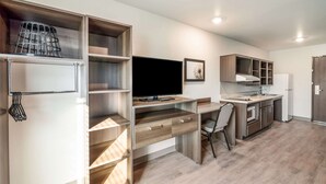 A modern kitchen with built-in appliances, a dining area, and a TV. - Woodspring Suites Tucson South (Tucson)