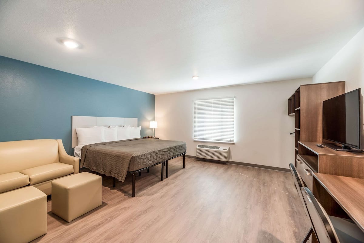 Una habitación de hotel moderna con cama, sofá, televisor y escritorio.